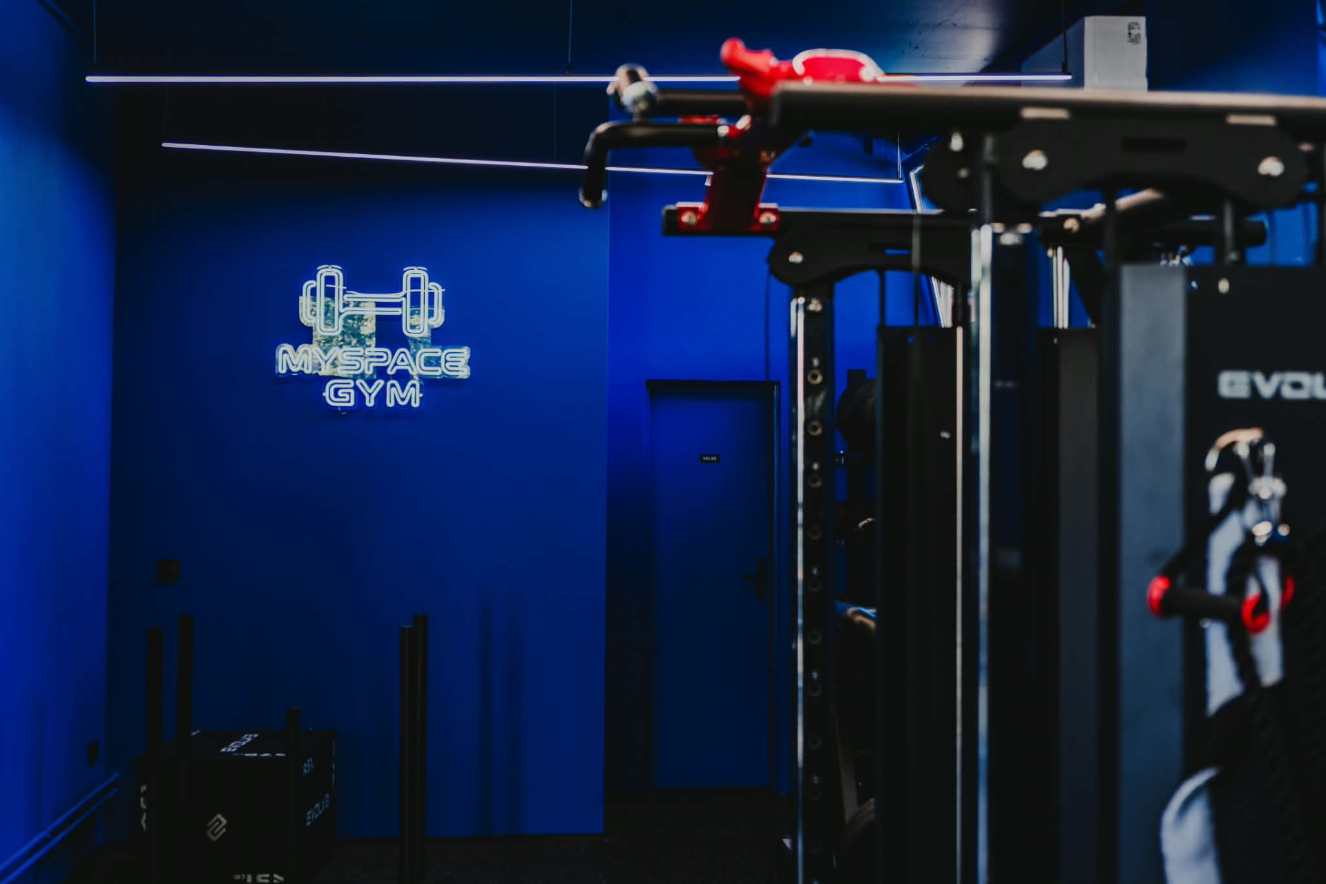 Neonový nápis MySpace GYM na modré stěně privátního fitness ve Vsetíně